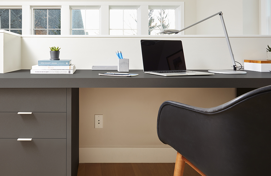 A desk chair in front of a desk with a laptop and drawers