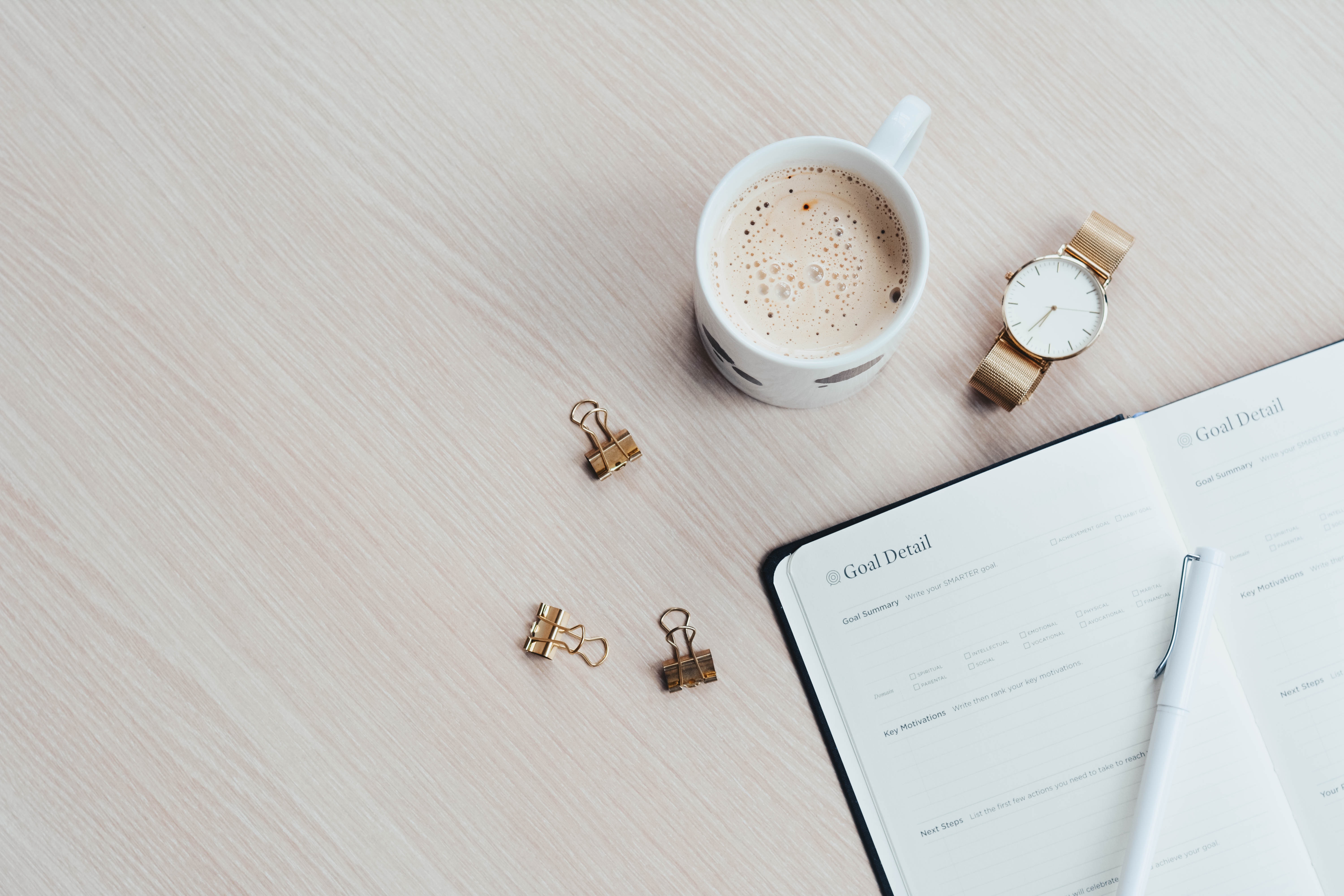 To do list written on a note pad with a coffee and pens next to it