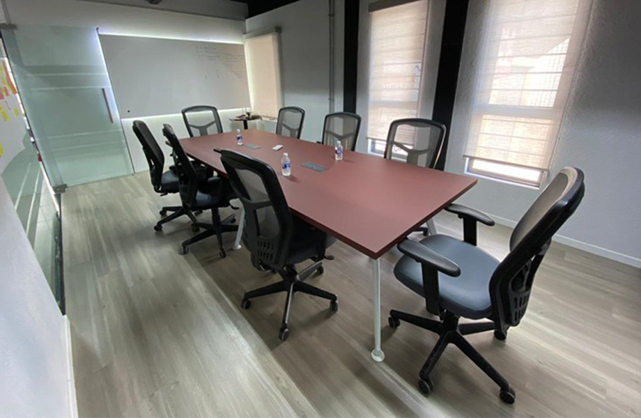 Boardroom table in LADE with FENIX Rosso Jaipur application, chairs and water bottles 