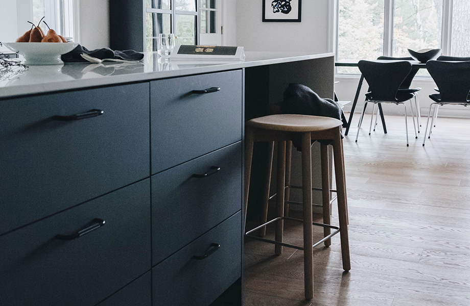 Gray Nordic Design cabinetry with white countertops, bar stool and table with a set of chairs