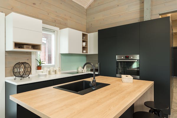 matte black open plan kitchen with a wooden island, a sink and chairs 