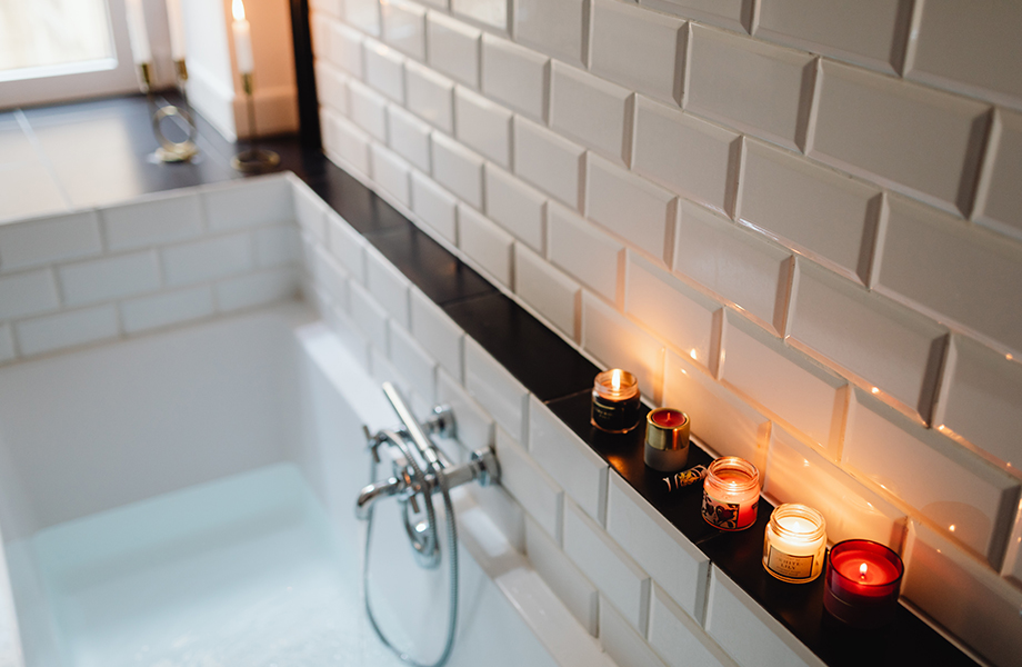 scented candles along the side of a bathtub