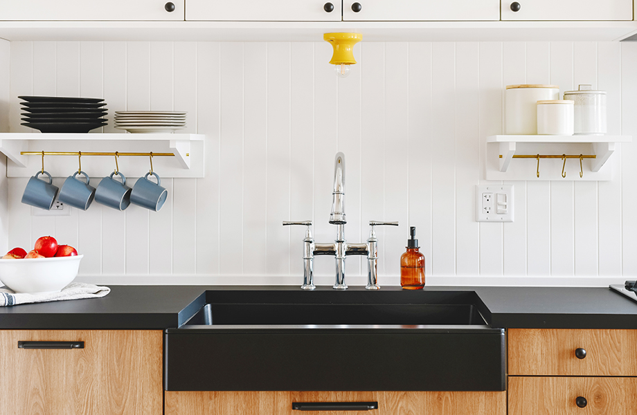 Modern kitchen with wooden cabinetry, black countertops and sink with kitchen accessories